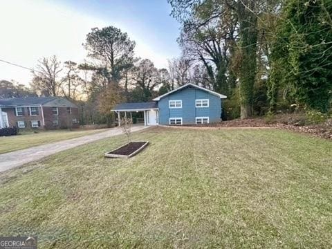 view of front facade with a front lawn, a carport, and concrete driveway