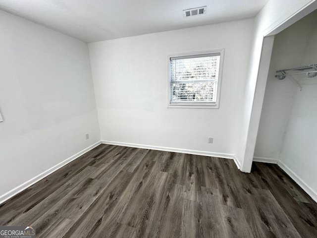 unfurnished bedroom with baseboards, a closet, visible vents, and dark wood-style flooring