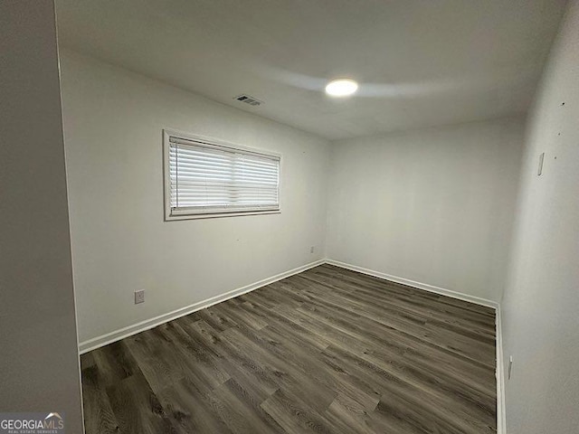 spare room with dark wood-style floors, baseboards, and visible vents