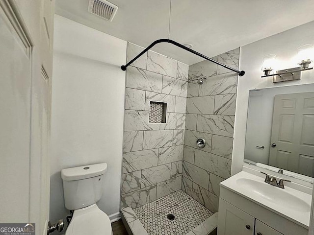 bathroom featuring vanity, toilet, and tiled shower