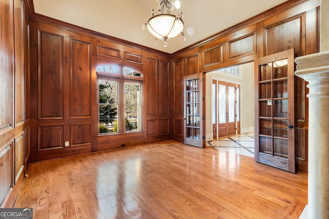 spare room featuring wooden walls, french doors, and light hardwood / wood-style flooring