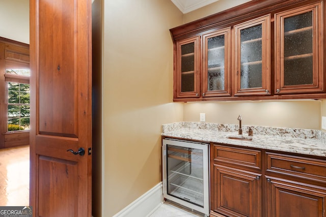 bar featuring light stone counters, sink, beverage cooler, and ornamental molding