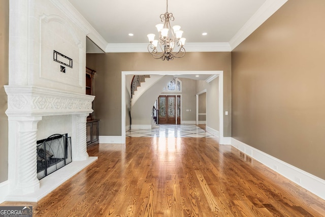 unfurnished living room with crown molding, french doors, a chandelier, and hardwood / wood-style flooring