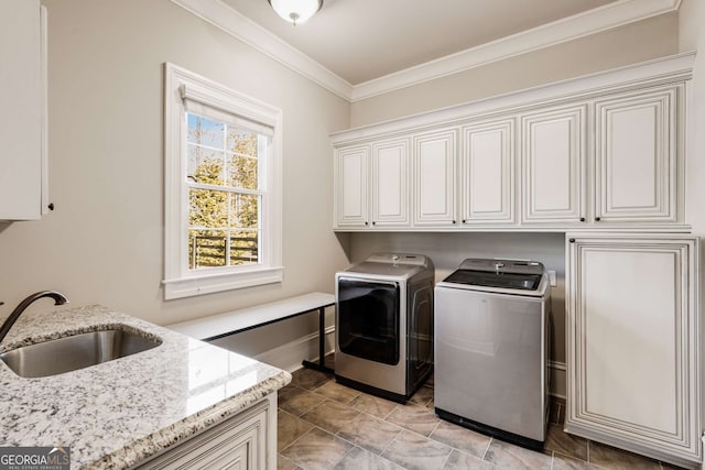 laundry room with washing machine and clothes dryer, crown molding, sink, and cabinets