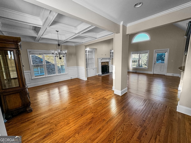 unfurnished living room with crown molding, beam ceiling, coffered ceiling, dark hardwood / wood-style flooring, and a chandelier