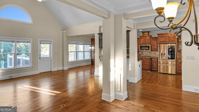 unfurnished living room featuring dark hardwood / wood-style flooring, high vaulted ceiling, ornamental molding, and a chandelier