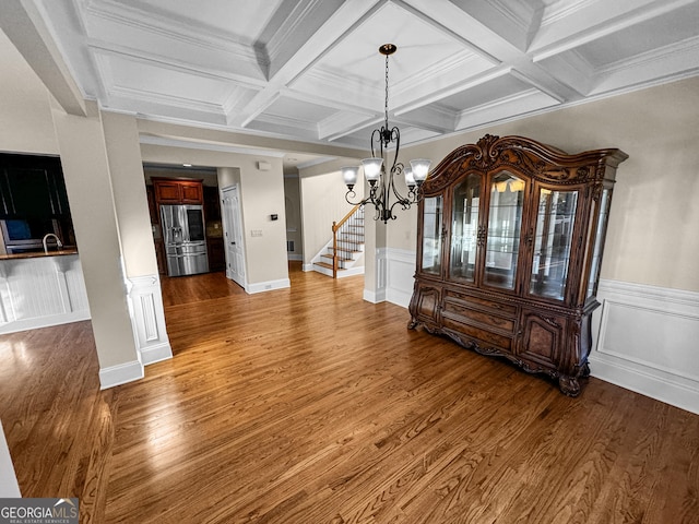 dining space with beamed ceiling, sink, hardwood / wood-style floors, and a notable chandelier