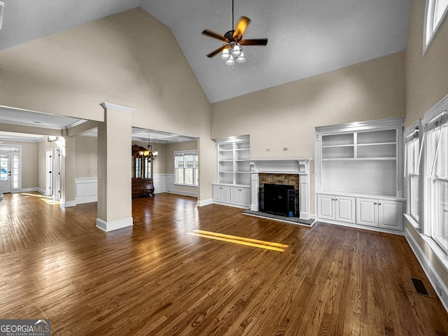 unfurnished living room with plenty of natural light, high vaulted ceiling, a fireplace, and dark hardwood / wood-style flooring