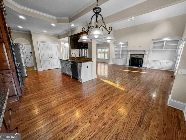 kitchen with sink, dark wood-type flooring, hanging light fixtures, black dishwasher, and a tray ceiling