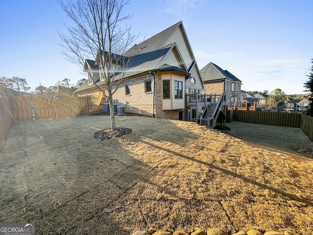 back of house with a wooden deck, a yard, and central air condition unit