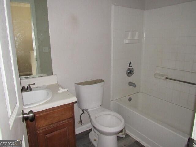 full bathroom with vanity, wood-type flooring, tiled shower / bath combo, and toilet