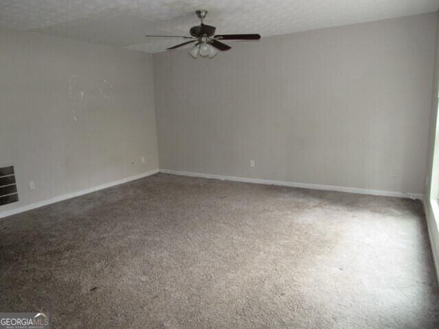 carpeted empty room featuring ceiling fan and a textured ceiling