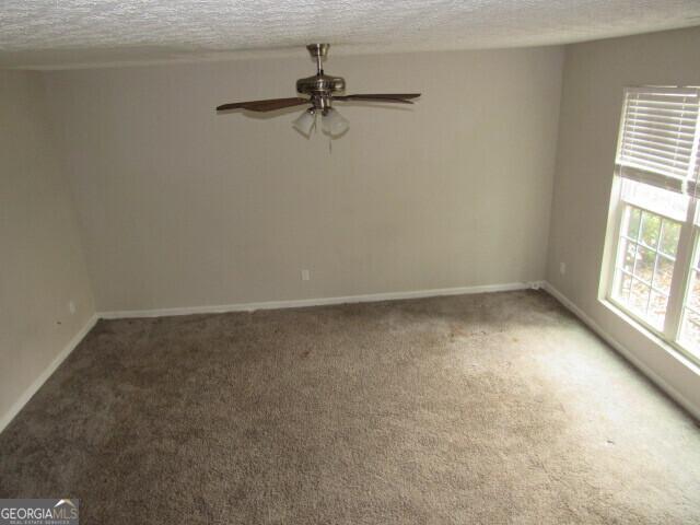 carpeted spare room with ceiling fan and a textured ceiling