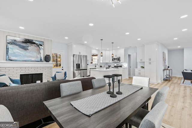 dining space with light hardwood / wood-style flooring and a brick fireplace