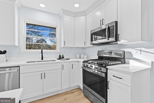 kitchen featuring white cabinetry, sink, stainless steel appliances, and light hardwood / wood-style flooring