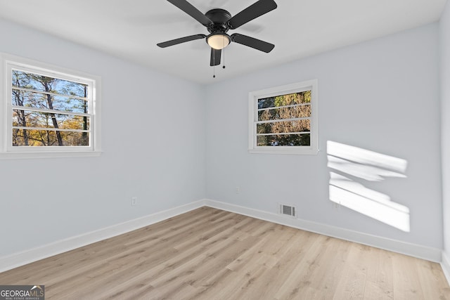 empty room with a wealth of natural light, ceiling fan, and light wood-type flooring