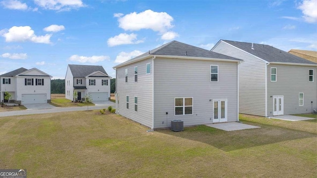 back of property with a yard, french doors, and a garage