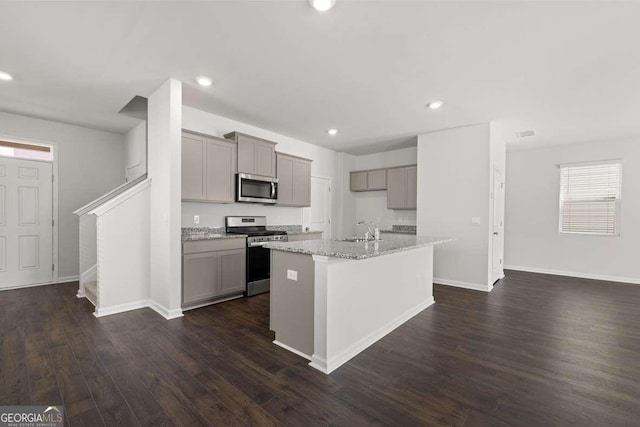 kitchen featuring appliances with stainless steel finishes, sink, gray cabinets, and an island with sink