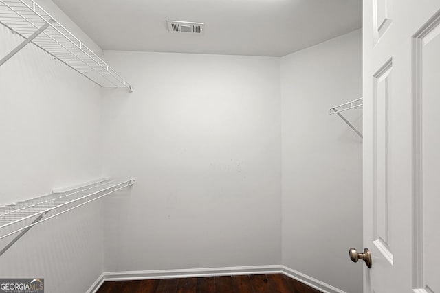 walk in closet with dark wood finished floors and visible vents