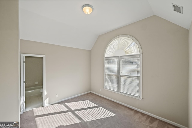 empty room featuring lofted ceiling, baseboards, visible vents, and carpet flooring