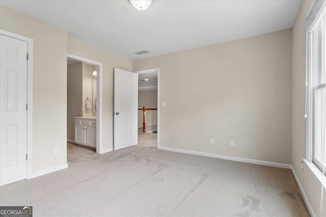 unfurnished bedroom featuring ensuite bath, baseboards, visible vents, and light colored carpet