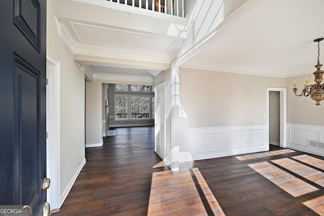 foyer entrance with crown molding, visible vents, an inviting chandelier, wainscoting, and hardwood / wood-style floors