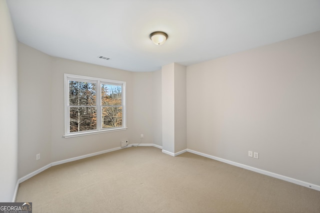 spare room featuring light carpet, visible vents, and baseboards