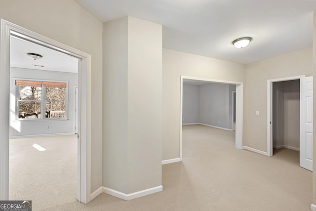 hall featuring light carpet and baseboards