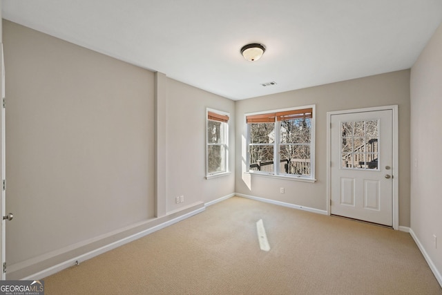 unfurnished room featuring visible vents, baseboards, and light colored carpet