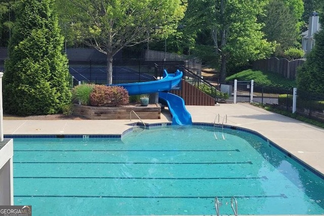 community pool featuring a water slide and fence