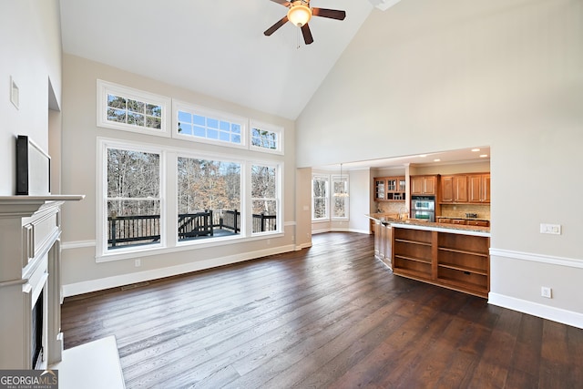 living area with baseboards, ceiling fan, a fireplace with flush hearth, dark wood-style flooring, and high vaulted ceiling