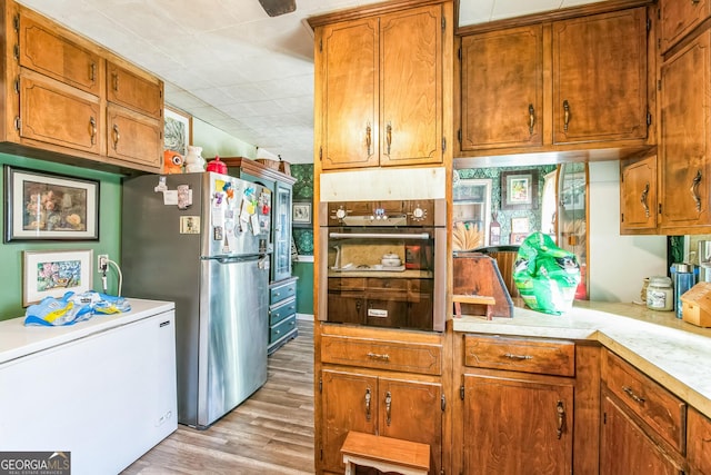 kitchen with wall oven, stainless steel refrigerator, light hardwood / wood-style flooring, and fridge