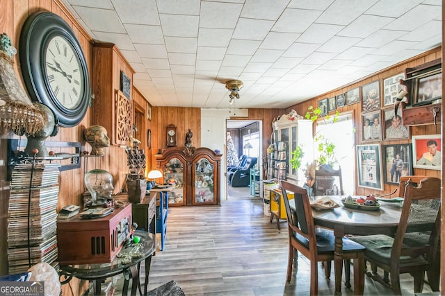 dining space with wood walls and wood-type flooring