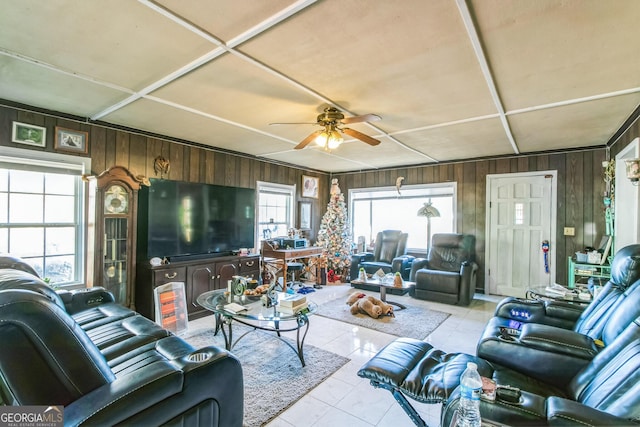 tiled living room featuring ceiling fan, wood walls, and a wealth of natural light