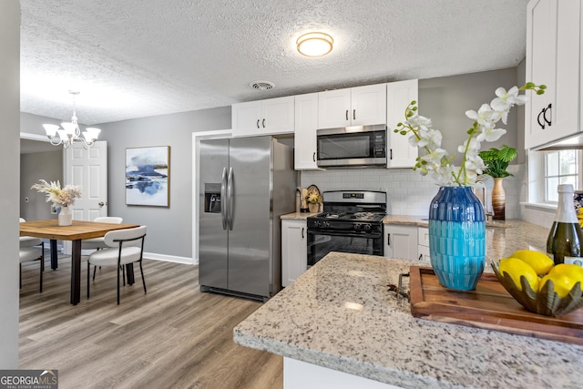 kitchen with white cabinets, decorative light fixtures, backsplash, and stainless steel appliances