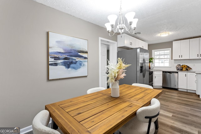 dining space featuring hardwood / wood-style flooring, sink, a textured ceiling, and a notable chandelier