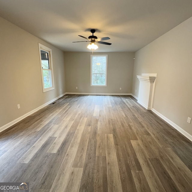 unfurnished living room with ceiling fan and dark wood-type flooring