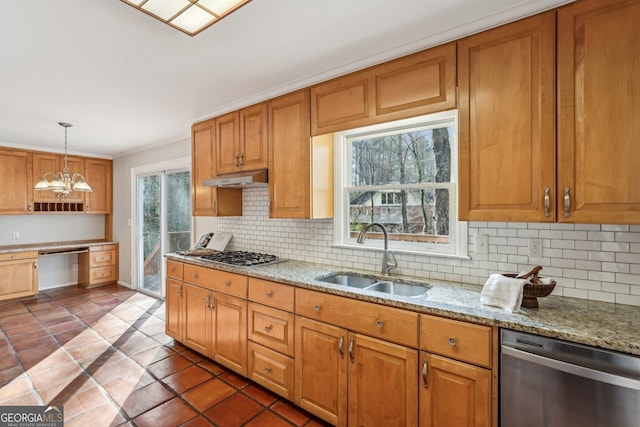 kitchen featuring sink, decorative light fixtures, appliances with stainless steel finishes, a notable chandelier, and light stone counters