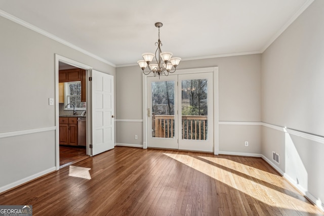 unfurnished dining area with dark hardwood / wood-style flooring, an inviting chandelier, ornamental molding, and sink