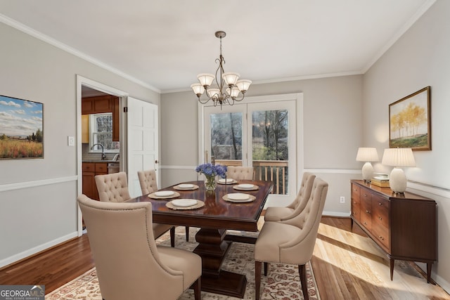 dining space with sink, light hardwood / wood-style flooring, a chandelier, and ornamental molding