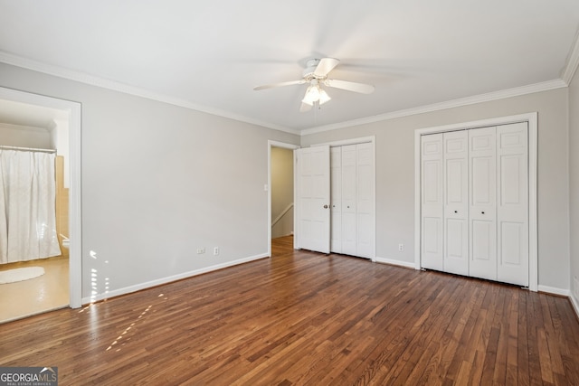 unfurnished bedroom featuring multiple closets, ceiling fan, dark hardwood / wood-style floors, and ornamental molding