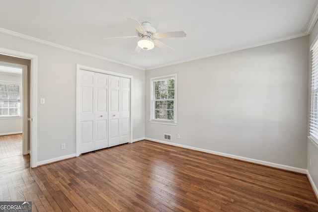 unfurnished bedroom featuring ornamental molding, a closet, ceiling fan, and dark wood-type flooring