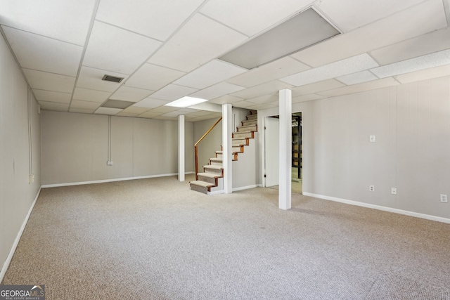 basement featuring a drop ceiling and light carpet