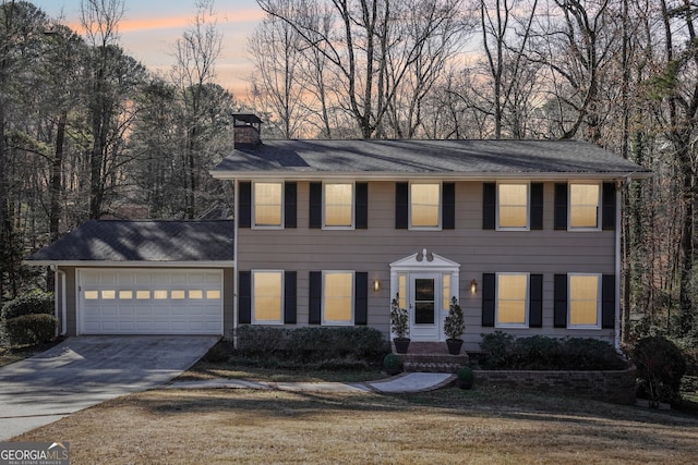 colonial inspired home featuring a garage and a lawn