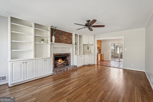 unfurnished living room featuring a fireplace, hardwood / wood-style floors, ceiling fan with notable chandelier, and ornamental molding