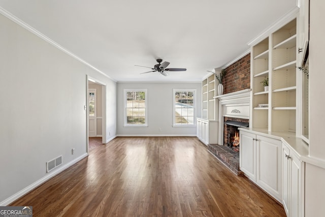 unfurnished living room featuring ceiling fan, dark hardwood / wood-style floors, crown molding, and a fireplace