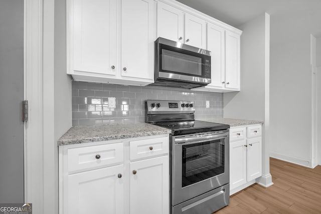 kitchen featuring light stone countertops, white cabinets, stainless steel appliances, tasteful backsplash, and light hardwood / wood-style flooring