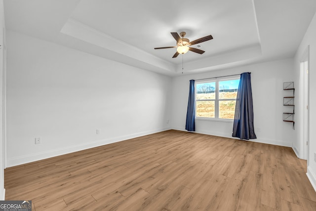 spare room with ceiling fan, light hardwood / wood-style flooring, and a raised ceiling