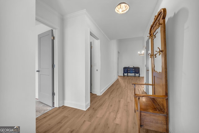 corridor with crown molding, a chandelier, and light hardwood / wood-style floors