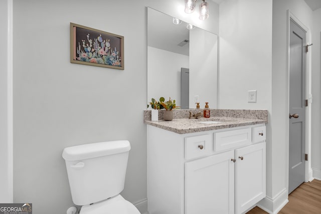 bathroom featuring wood-type flooring, toilet, and vanity